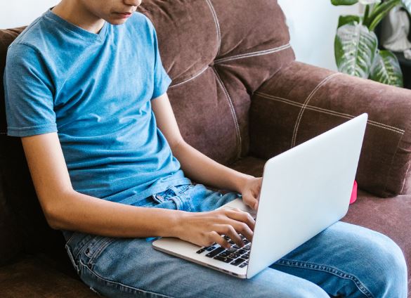 Man sitting on couch using laptop